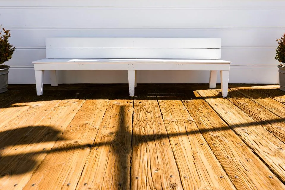 White outdoor bench on a sunlit timber deck